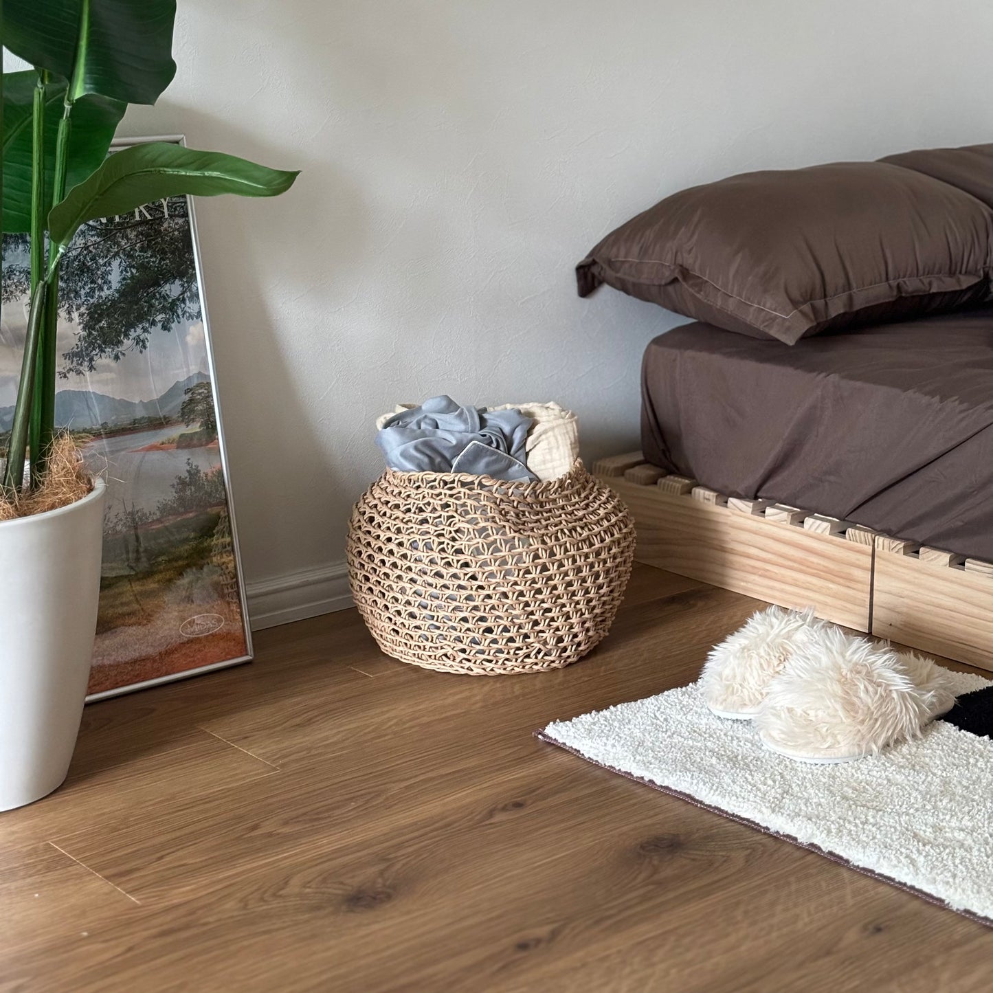 ラウンドのペーパーコードバスケットの中にパジャマやブランケットを入れてベッド横に置いている様子