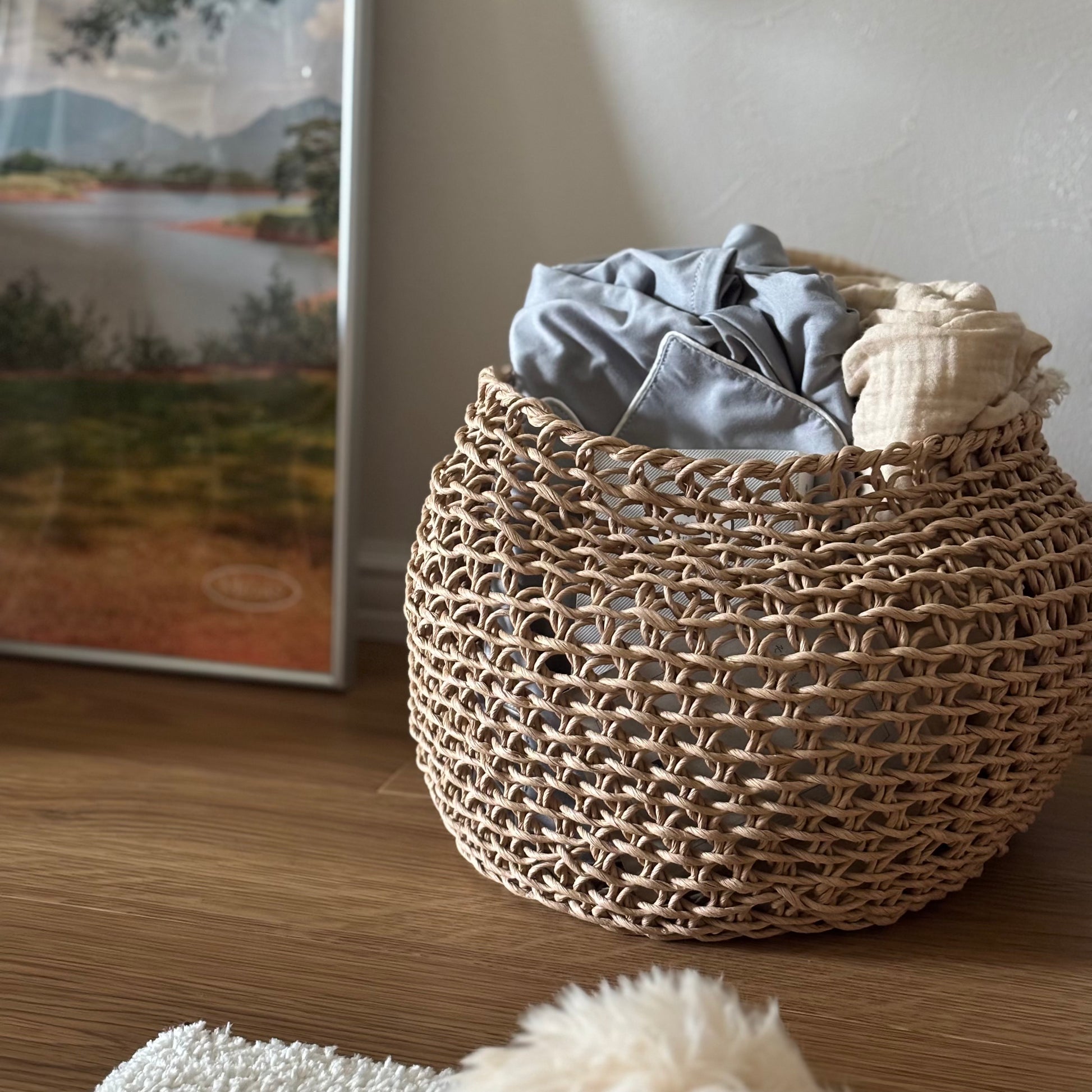 ラウンドのペーパーコードバスケットの中にパジャマやブランケットを入れている様子