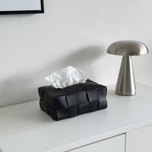 黒のレザーの編み込みのティッシュボックスが白い棚の上に置かれている様子
