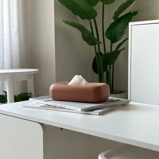 雑誌の上に茶色のシリコンのティッシュケースが置かれてある