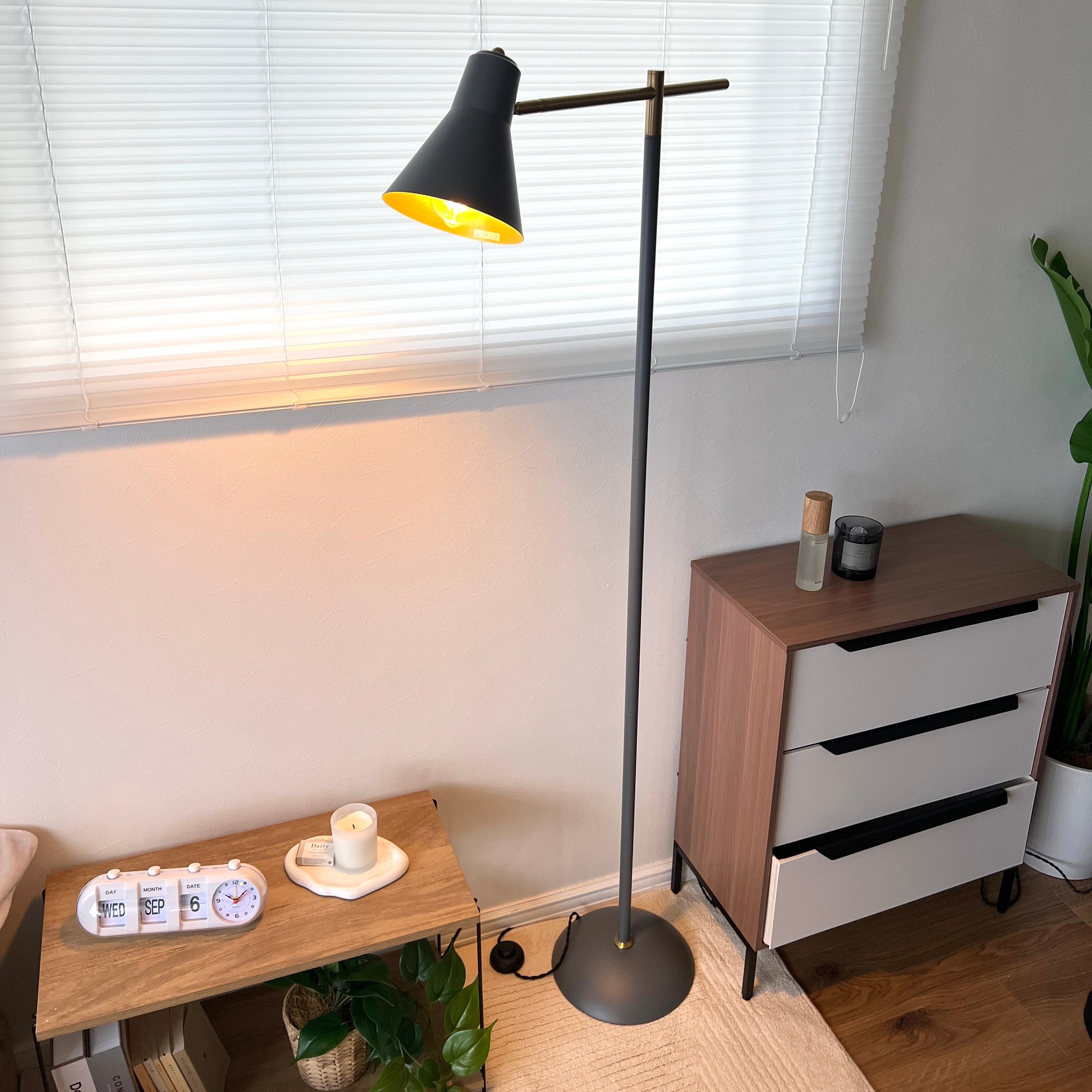 グレーのスチール製のフロアライトの電気をつけて部屋に置いている様子