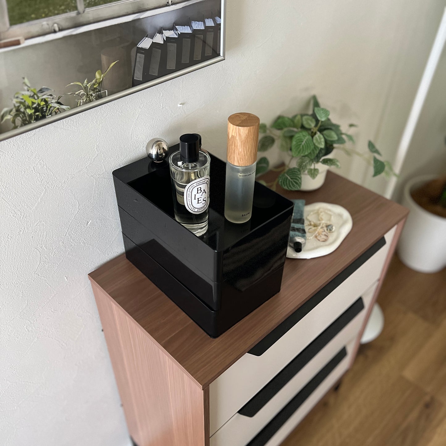 部屋の中でチェストの上に黒い3段の収納ケースが乗っている様子