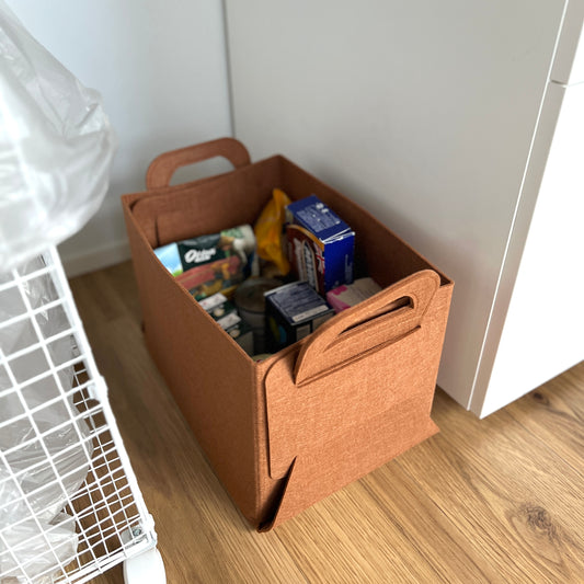 ブラウンのフェルトバスケットに食料品を収納している様子