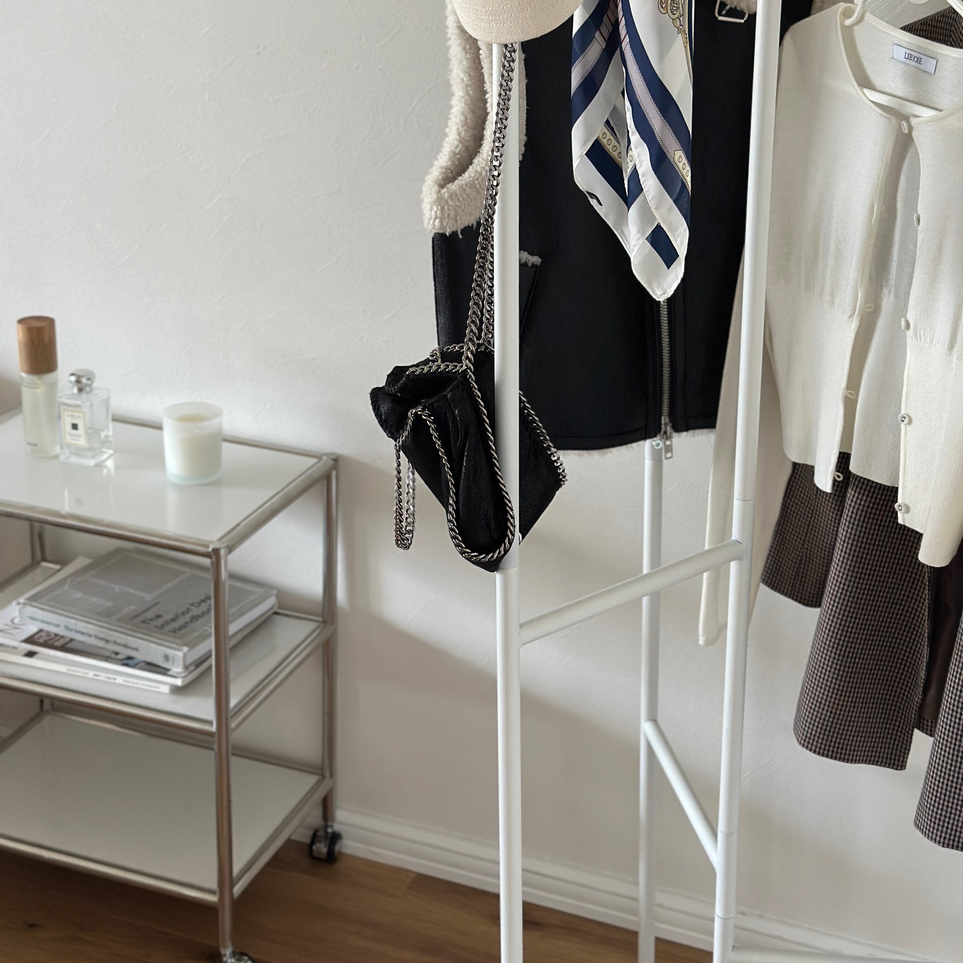部屋の中で折り畳めるスタイリッシュなパーテーションハンガーに洋服やバッグが飾ってある様子