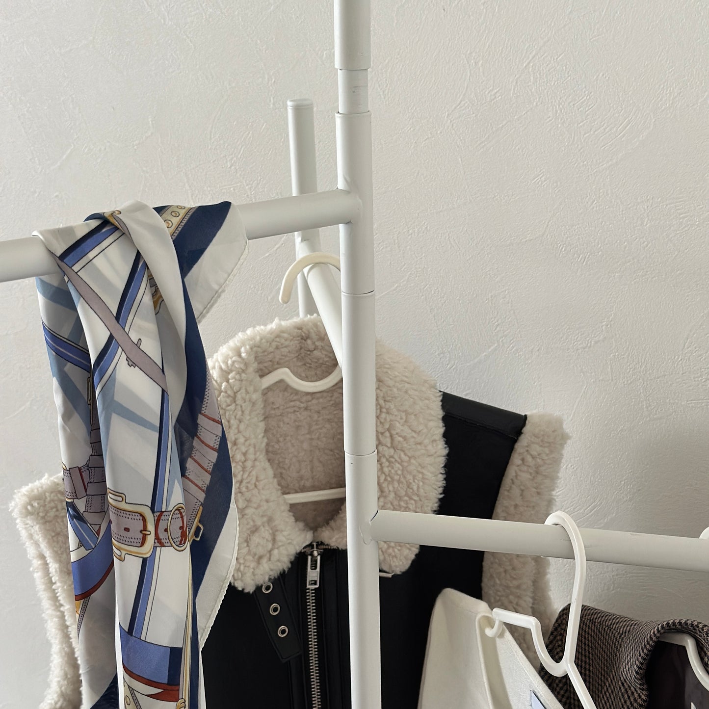 部屋の中で折り畳めるスタイリッシュなパーテーションハンガーに洋服やバッグが飾ってある様子