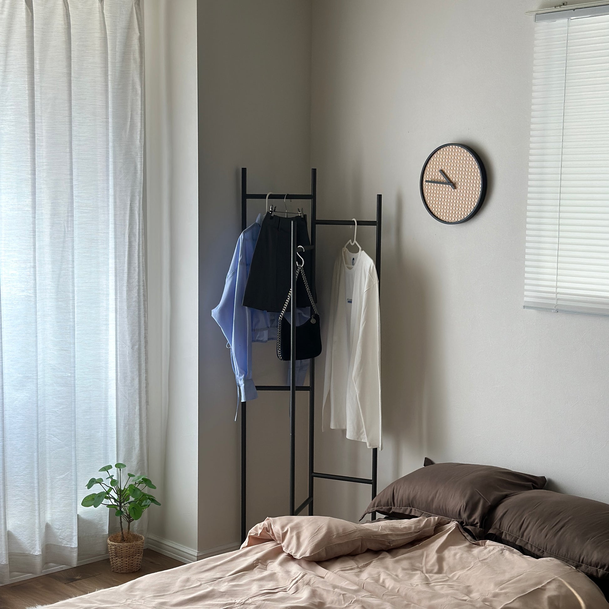 部屋の中で折り畳めるスタイリッシュなパーテーションハンガーに洋服やバッグが飾ってある様子