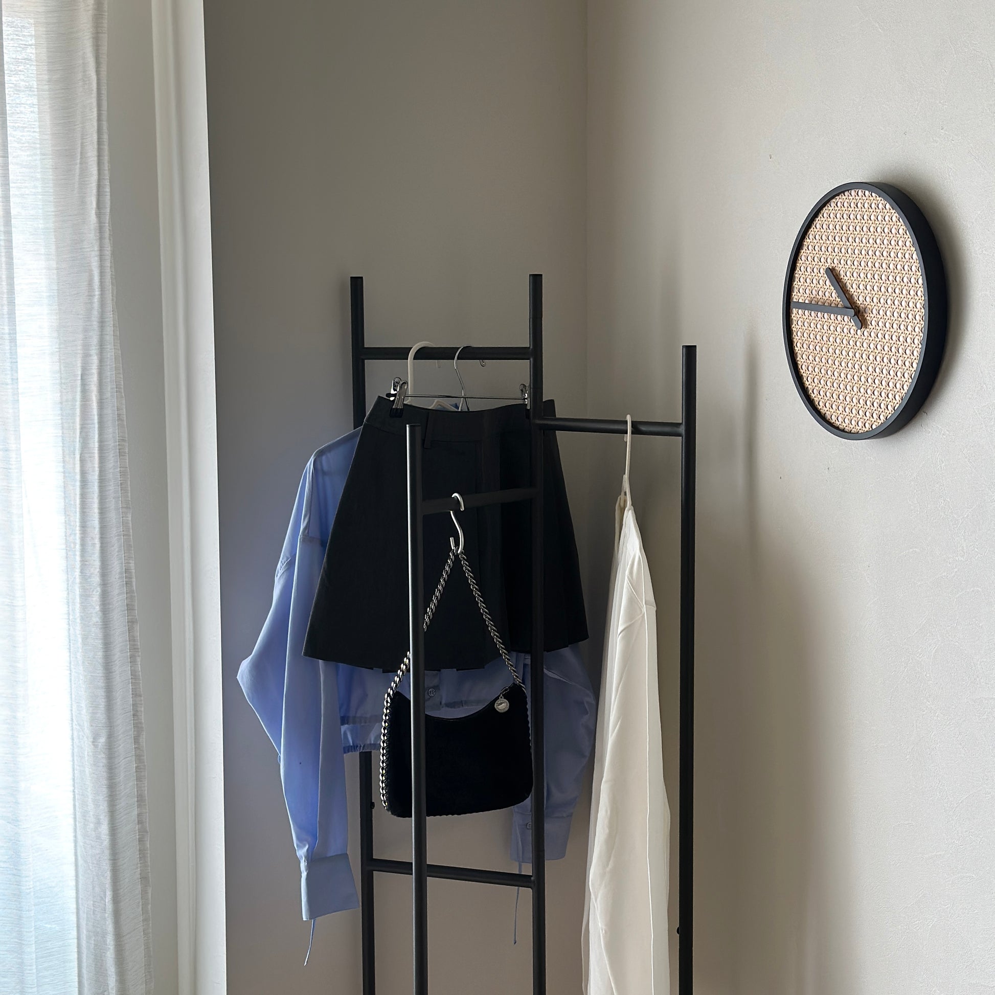 部屋の中で折り畳めるスタイリッシュなパーテーションハンガーに洋服やバッグが飾ってある様子