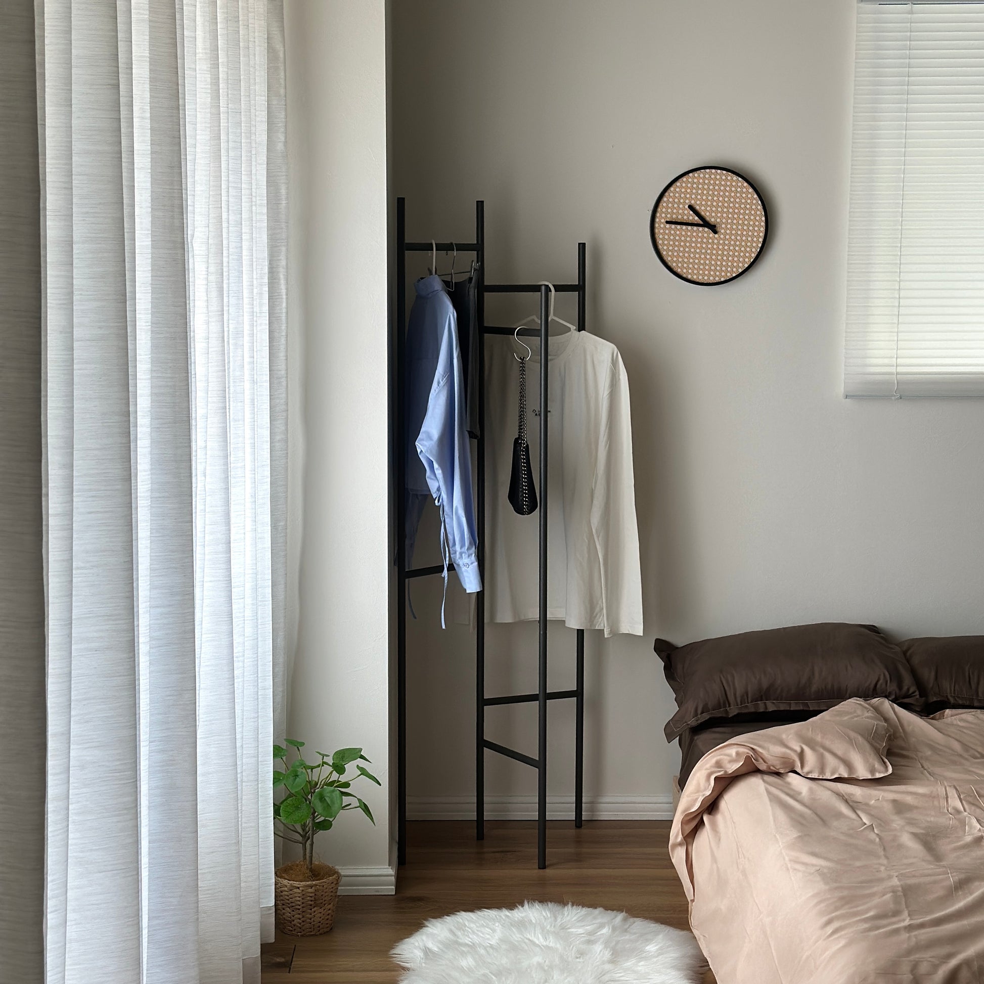 部屋の中で折り畳めるスタイリッシュなパーテーションハンガーに洋服やバッグが飾ってある様子