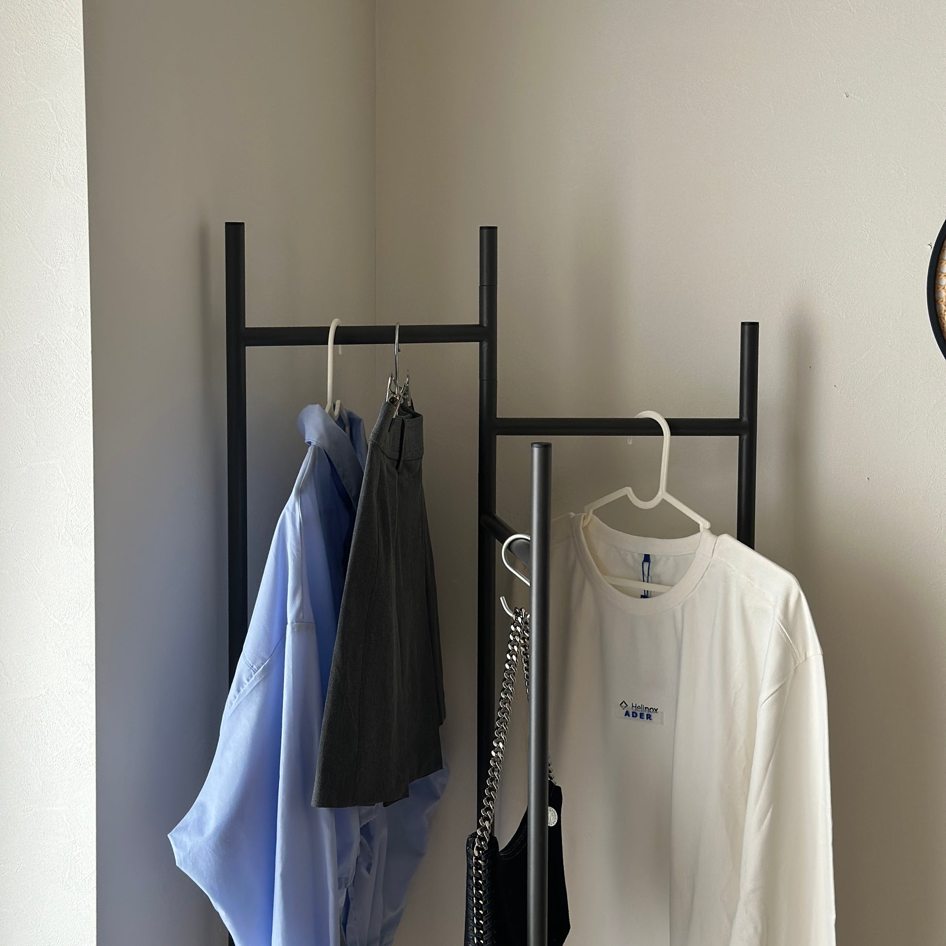 部屋の中で折り畳めるスタイリッシュなパーテーションハンガーに洋服やバッグが飾ってある様子