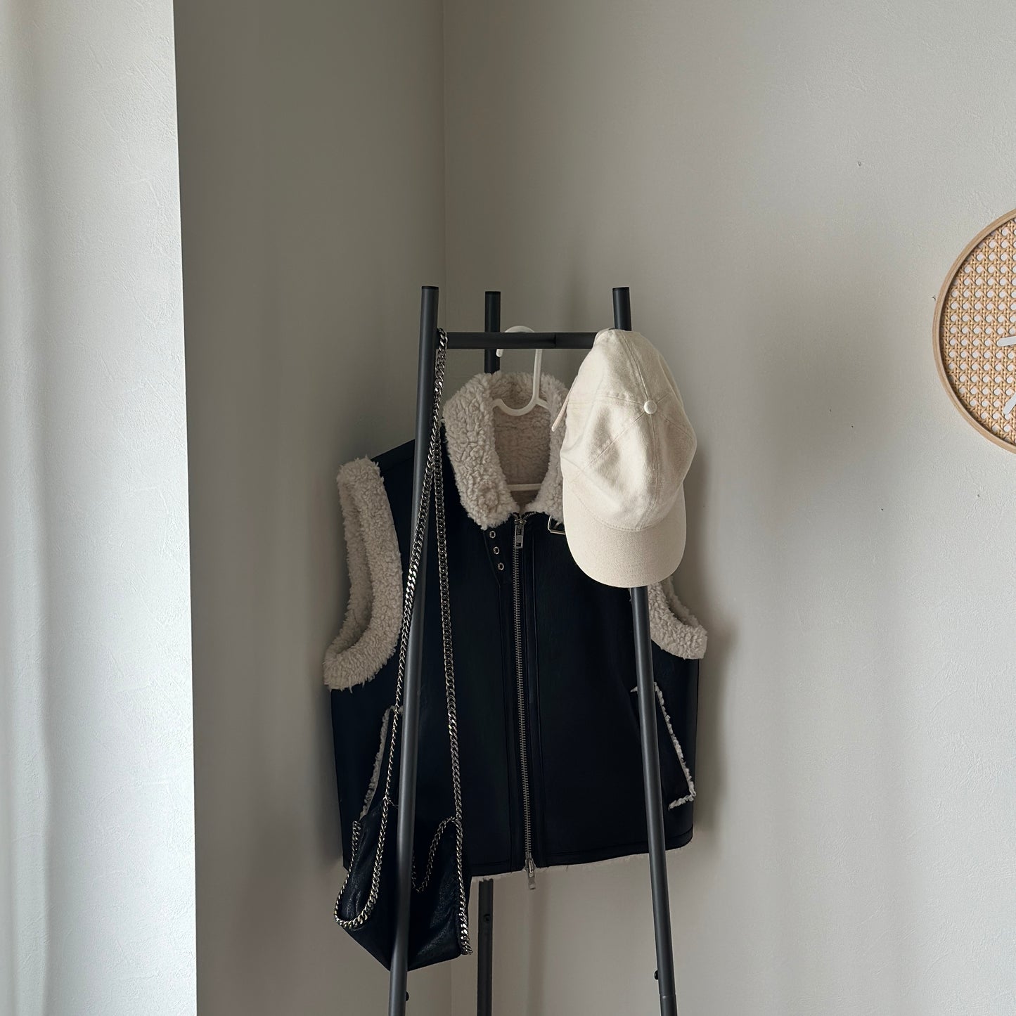 部屋の中で黒いコンパクトでスタイリッシュなハンガーラックに洋服がかかっている様子
