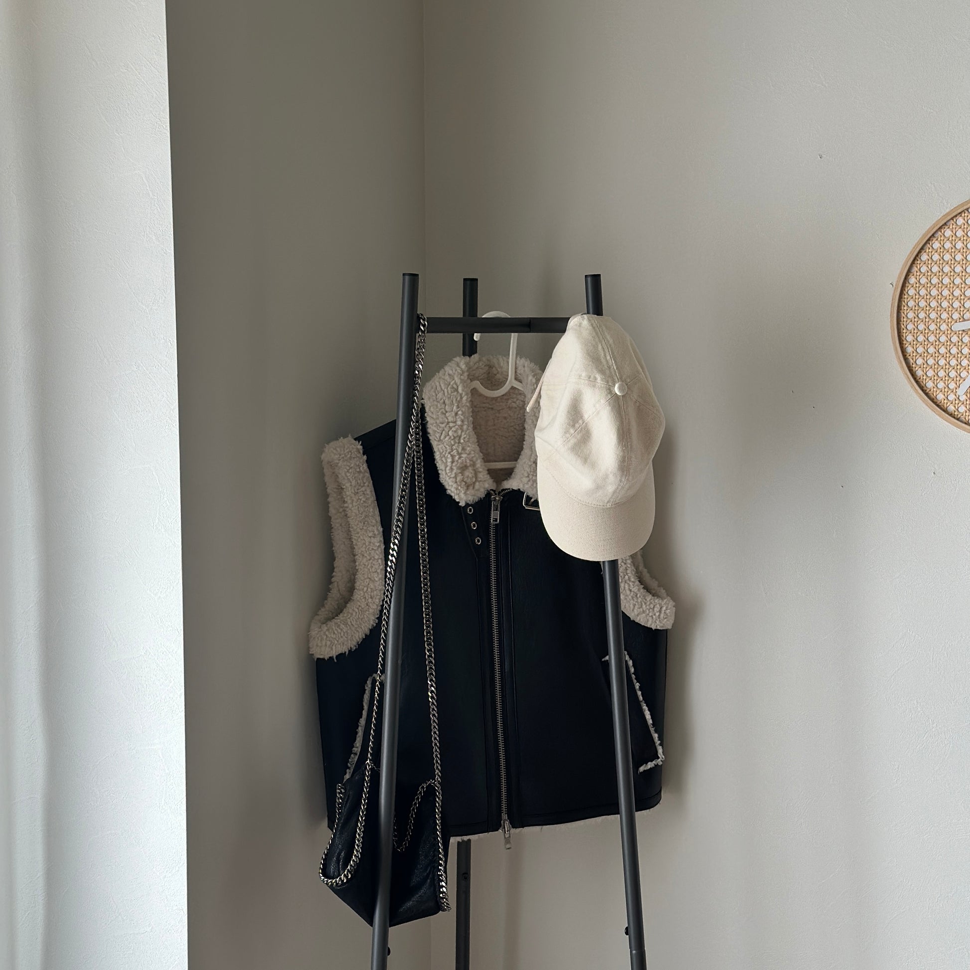 部屋の中で黒いコンパクトでスタイリッシュなハンガーラックに洋服がかかっている様子