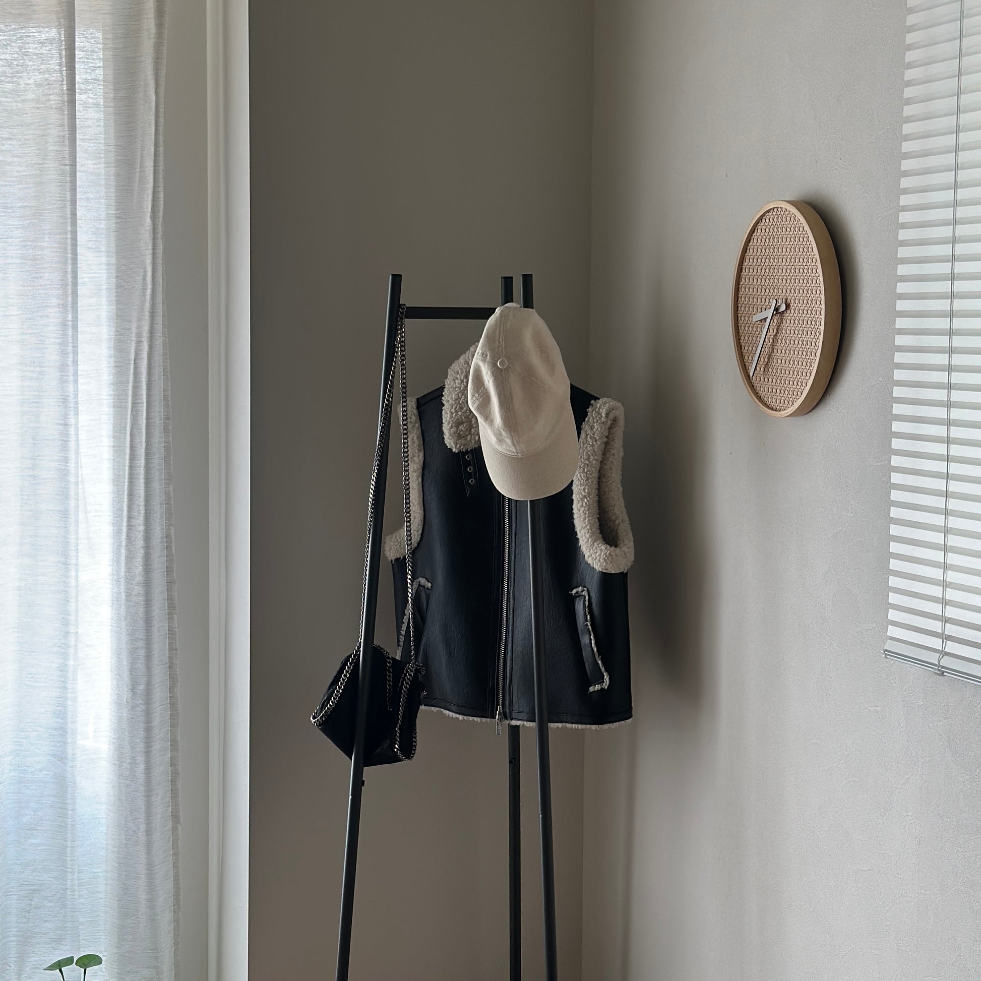 部屋の中で黒いコンパクトでスタイリッシュなハンガーラックに洋服がかかっている様子