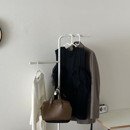 部屋の中で白の回転式ポールハンガーに洋服が飾られている様子