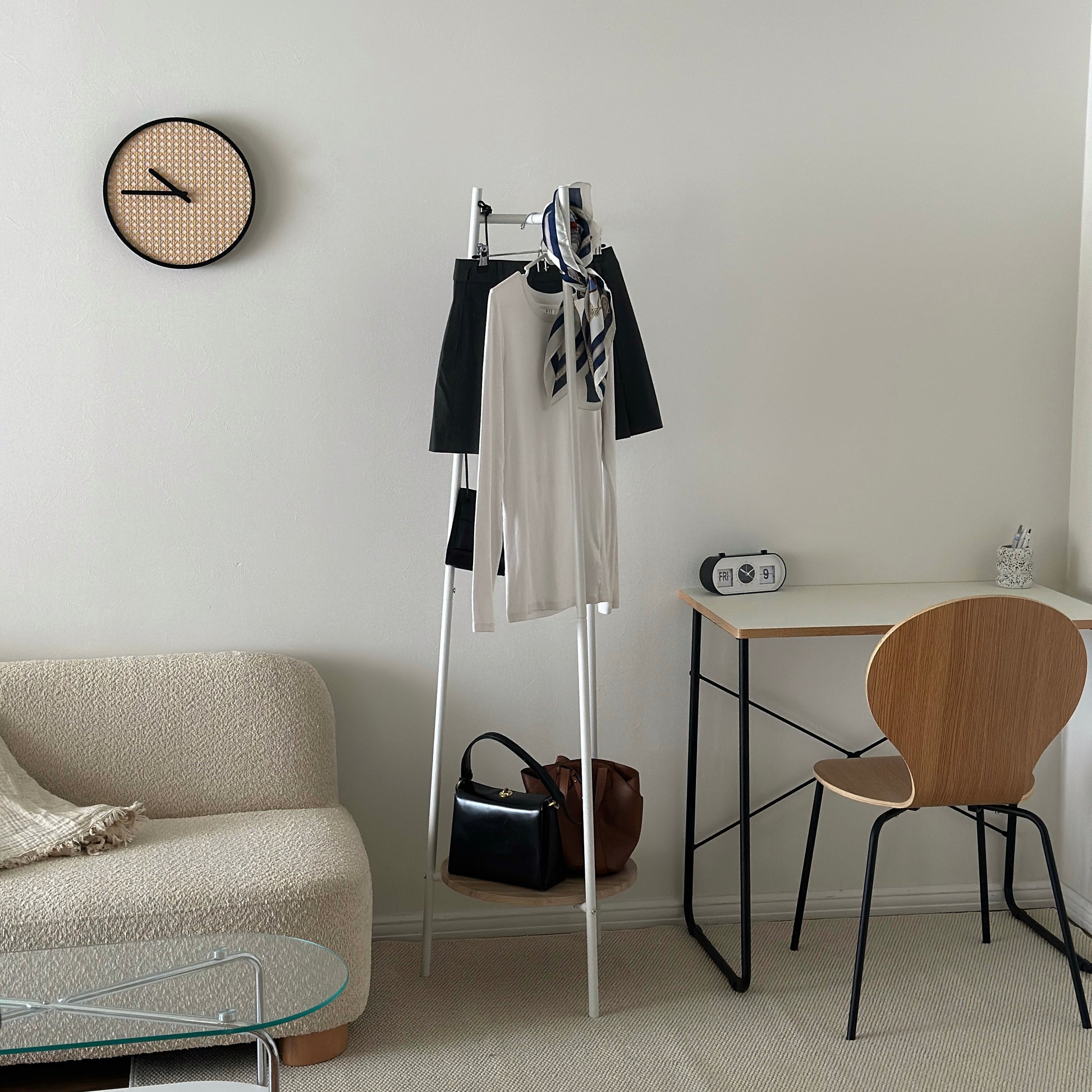 部屋の中で白いコンパクトでスタイリッシュなハンガーラックに洋服がかかっている様子