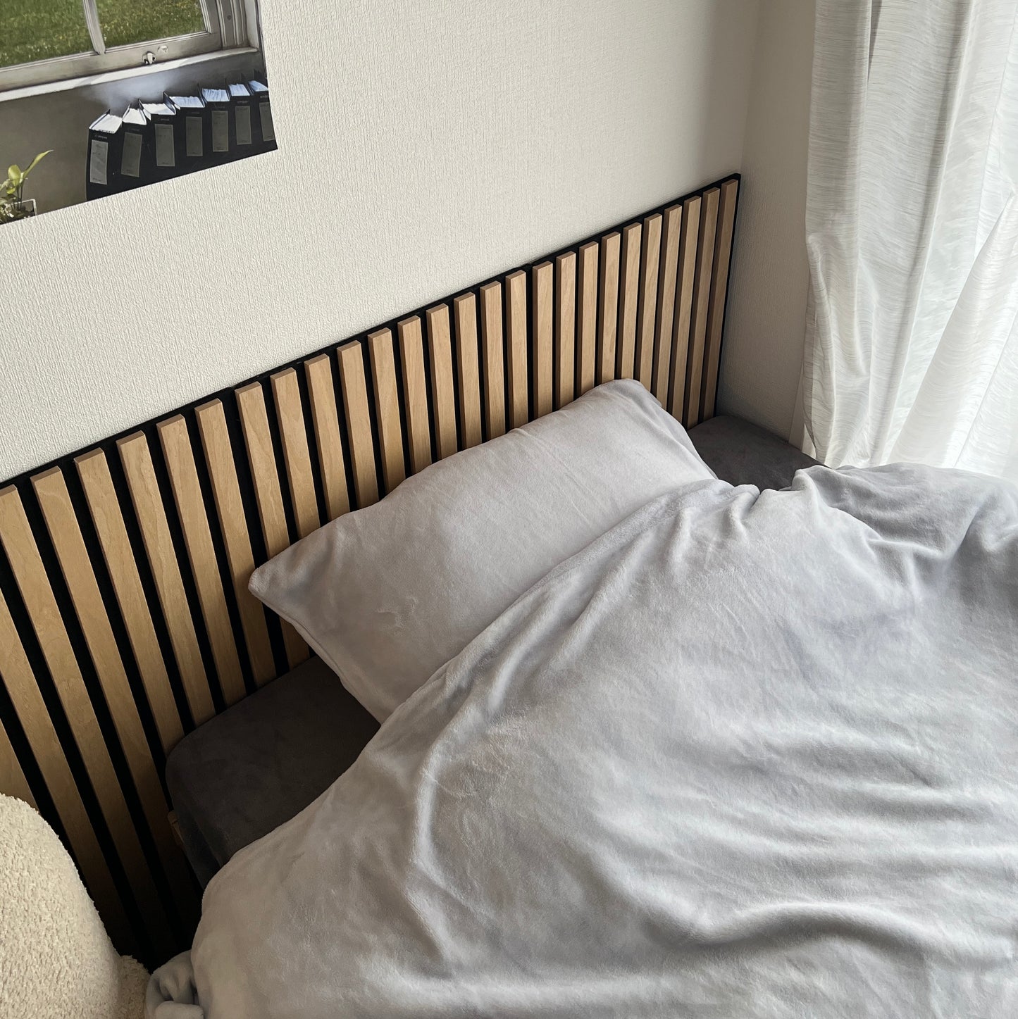 ベッドと壁の間に吸音パネルが置いてある部屋