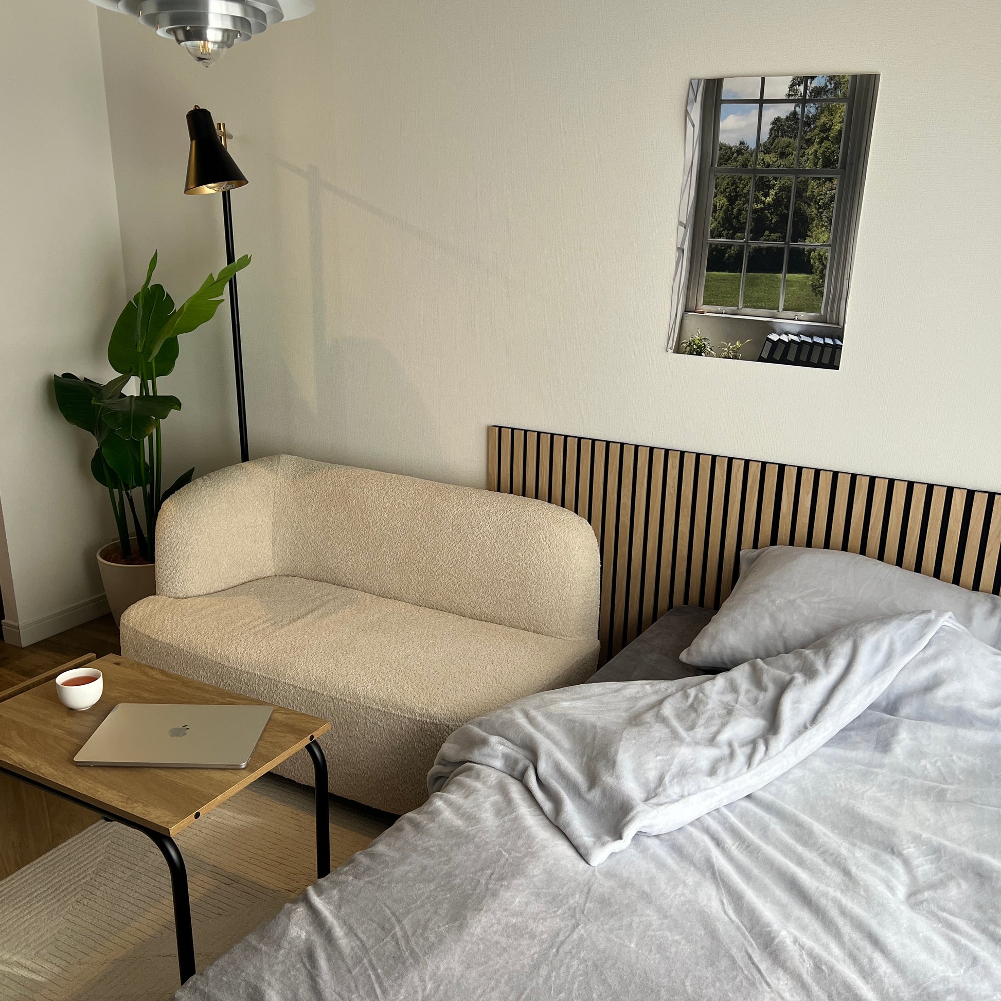 ６畳の空間にベッドとソファの裏に吸音パネルが置いてあるお洒落な部屋