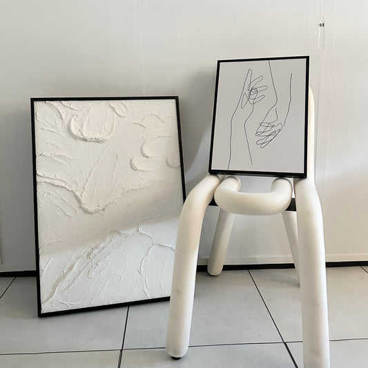 椅子の上に乗せられた2つの手が描かれたアートと、その横に一回り大きいテクスチャーアートが置かれている写真