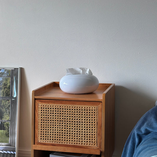 光沢のある丸みを帯びたホワイトのティッシュケースをベッドサイドテーブルに置いている様子