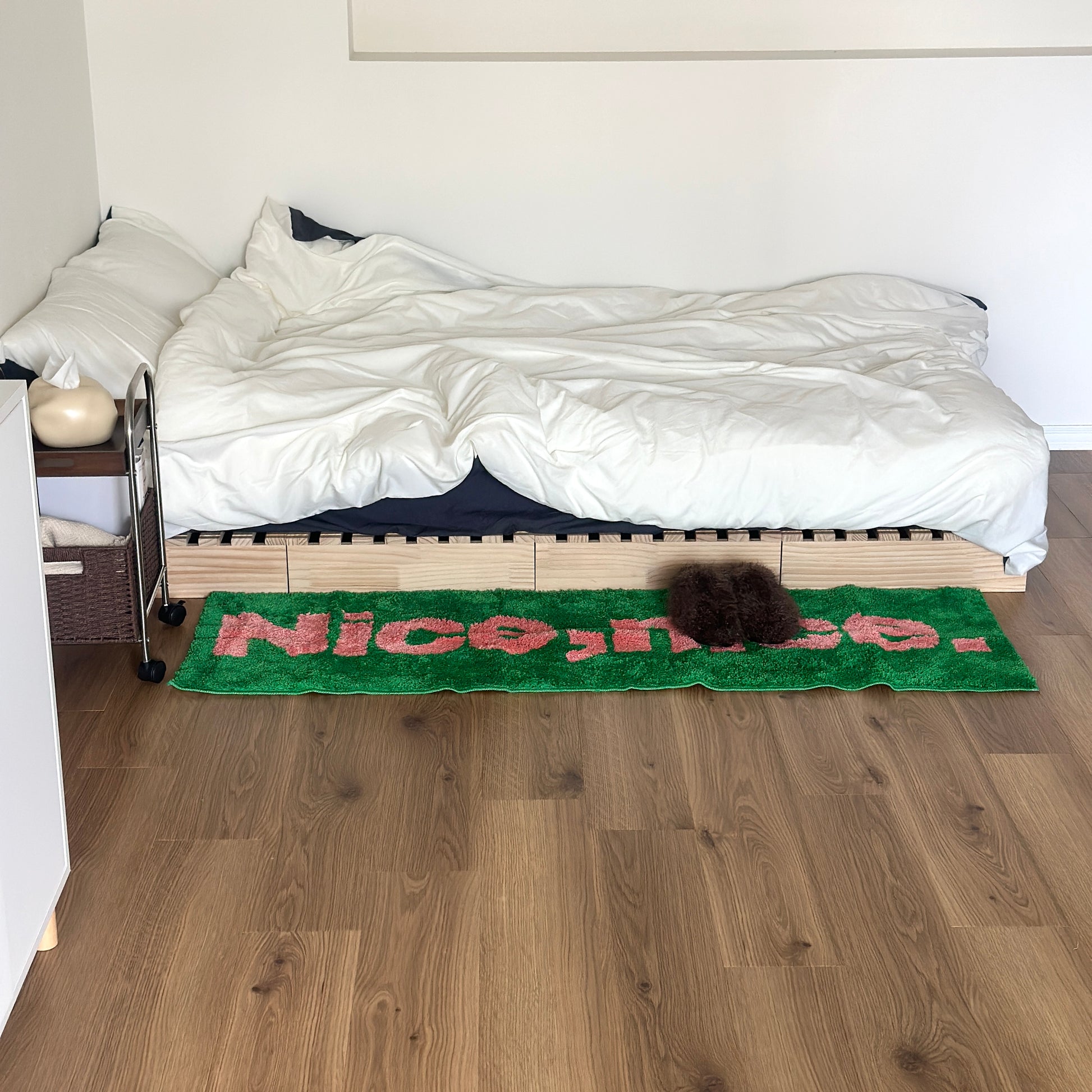 Nice,nice.のレタリングがされているグリーンのロングラグがベッド横に敷かれている様子