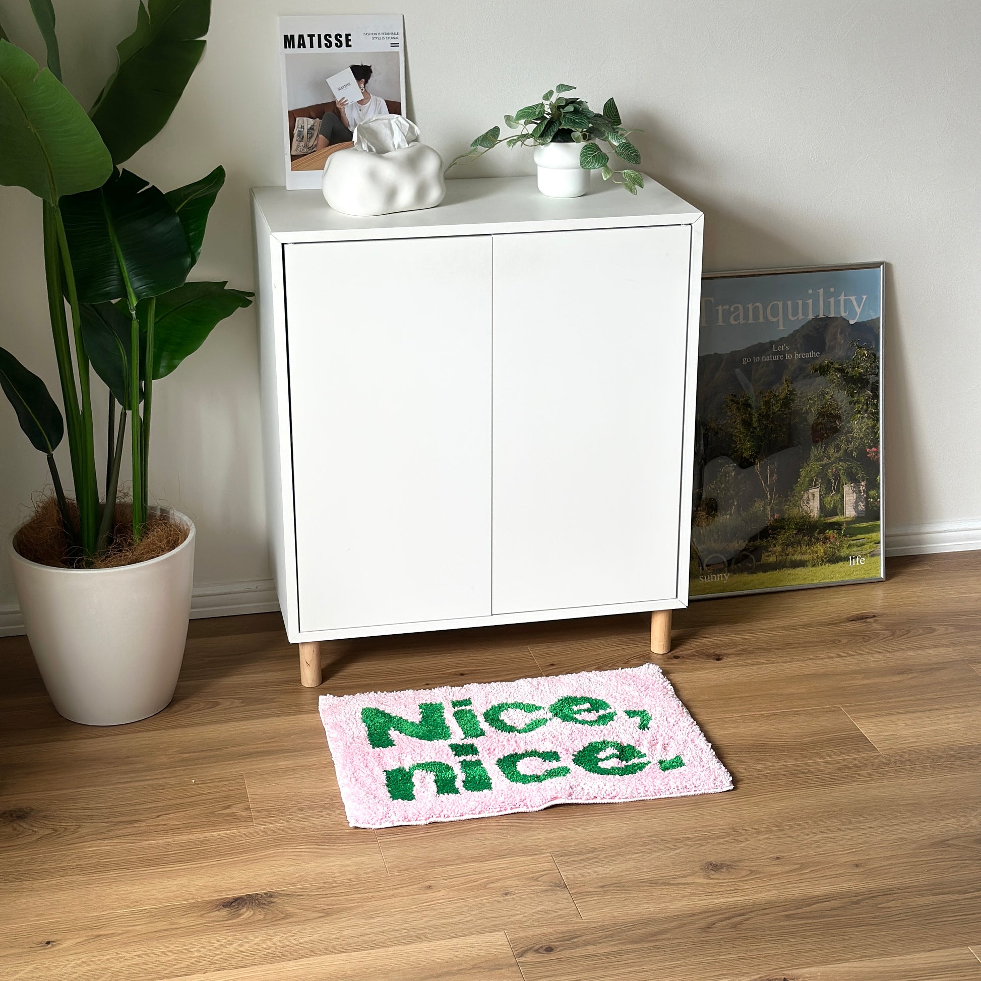 Nice,nice.のレタリングがされてあるピンクのミニラグを白棚の前に敷いている様子