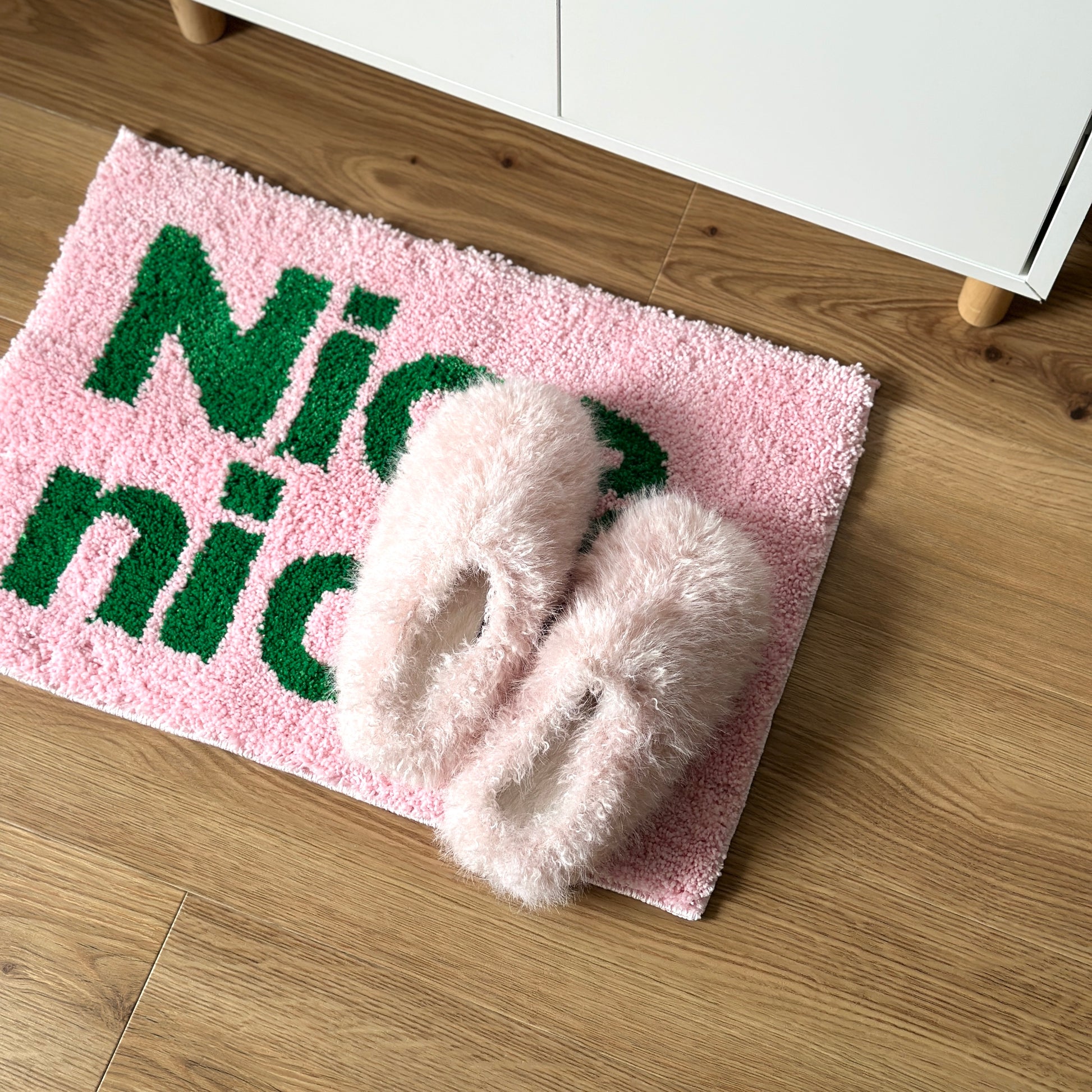 ピンクのもこもこのスリッパをピンクのミニラグの上に置いている様子