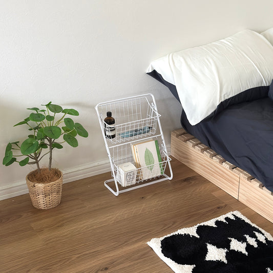 2段のホワイトのワイヤーバスケットラックをベッド横に置いている様子