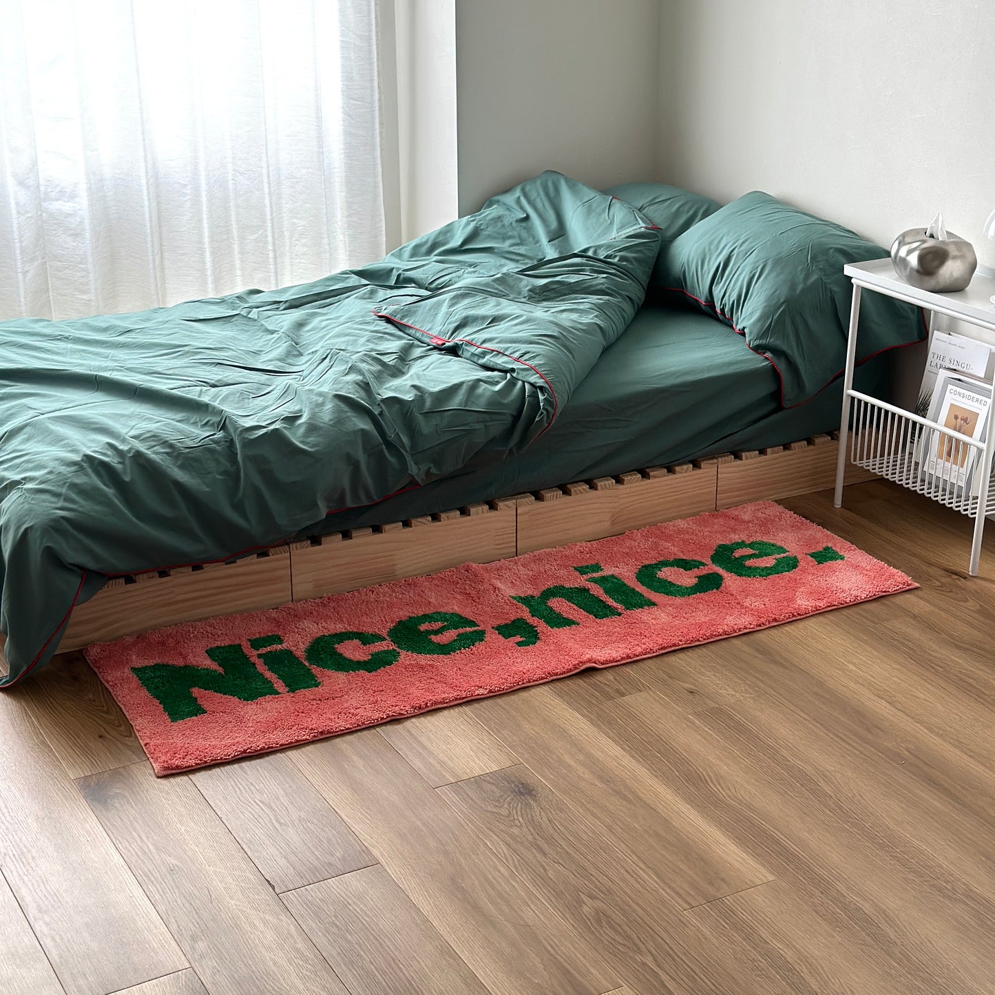 Nice,nice.のレタリングがされてあるピンクのロングラグをベッド横に敷いている様子