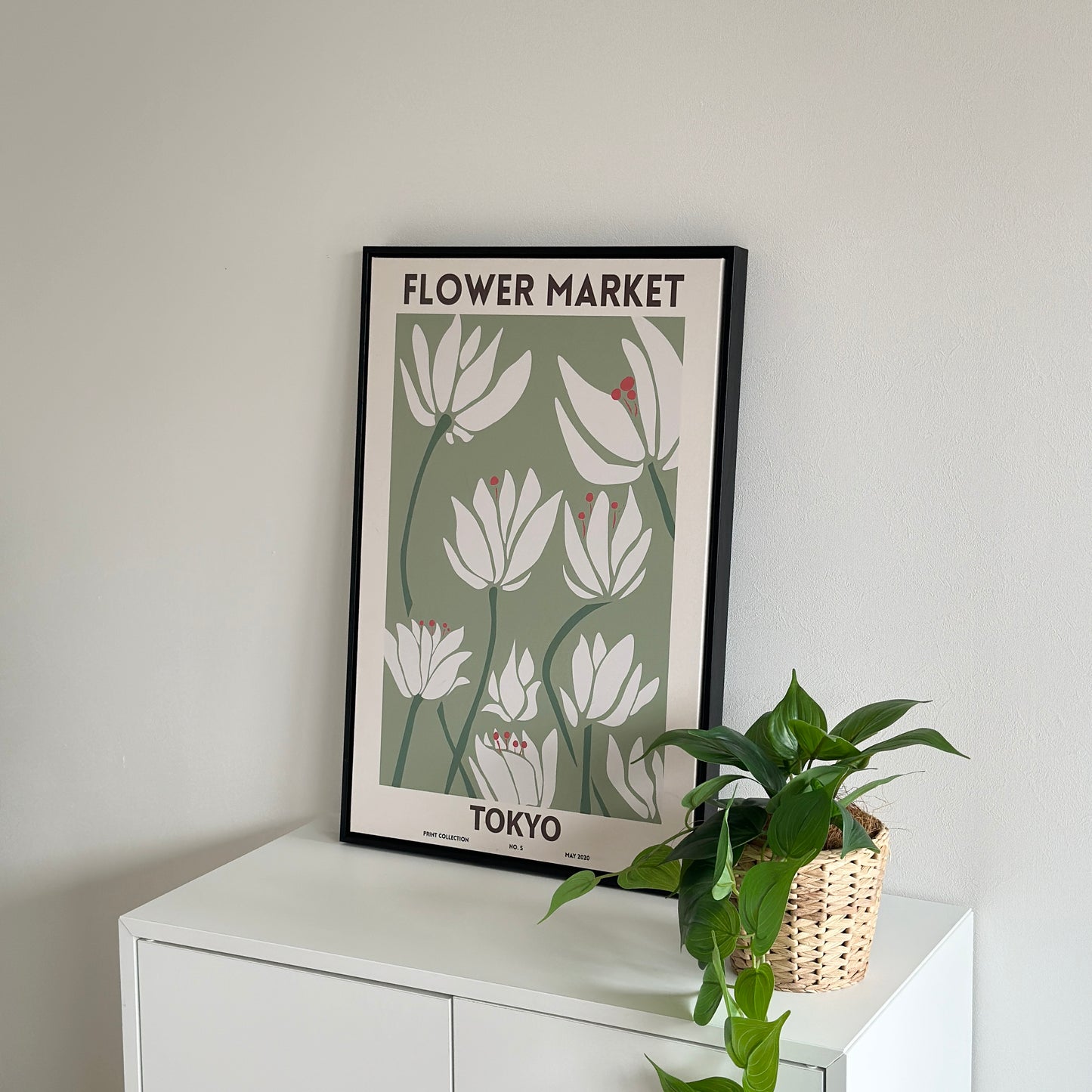 棚の上に置かれたグリーンを基調とした花のイラストが描かれたアートと植物