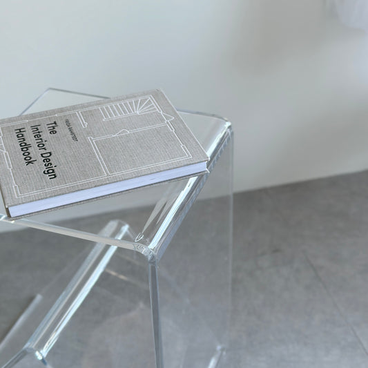 ユニークな形の透明なサイドテーブルに本を乗せている様子