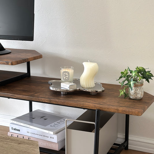 茶色い木目のテレビボードの上に、縁がウェーブ状になっている脚付きのシルバープレートが置かれてある。そのプレートの上にキャンドルが2つ置かれてある。