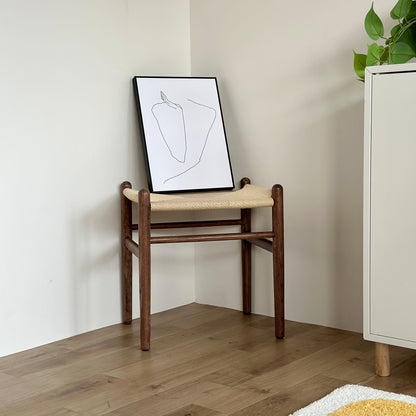 ブラウンカラーの、座面がペーパーコードで施されたウッド素材のスツールの上にアートが置かれてある様子