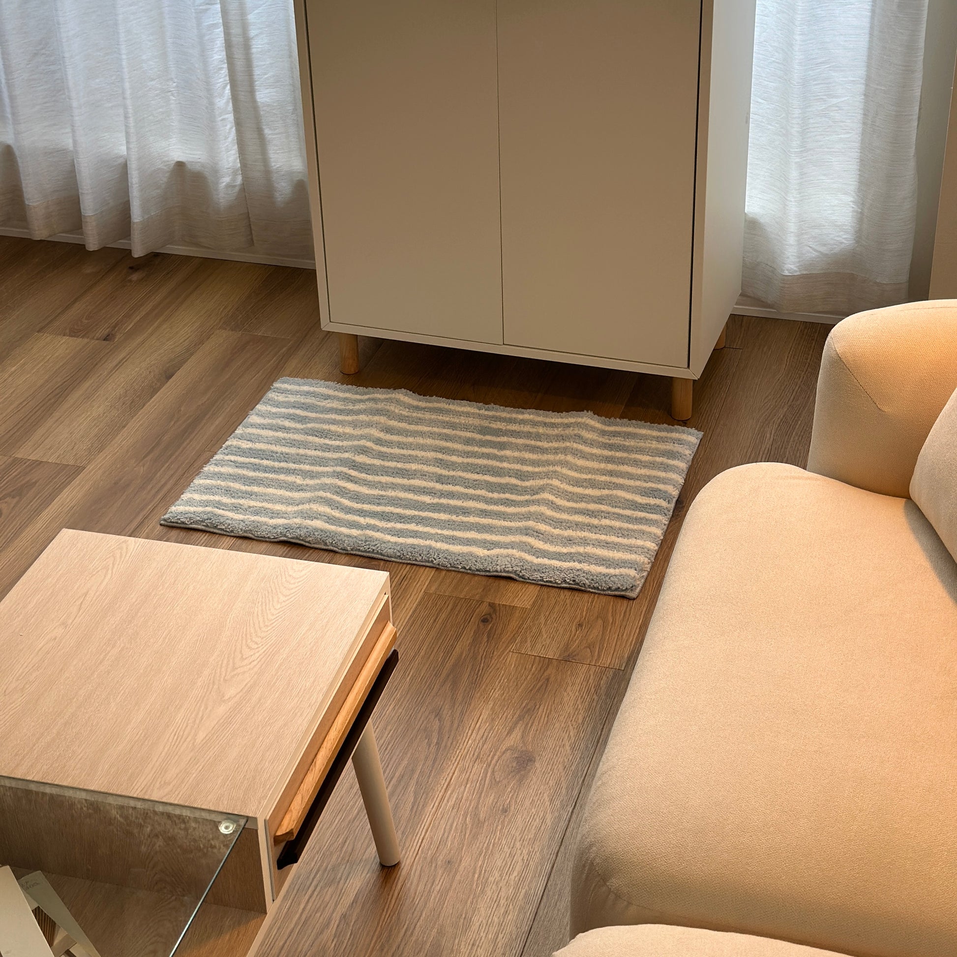 ライトブルーのシンプルなボーダーミニラグを白棚の前に敷いている様子