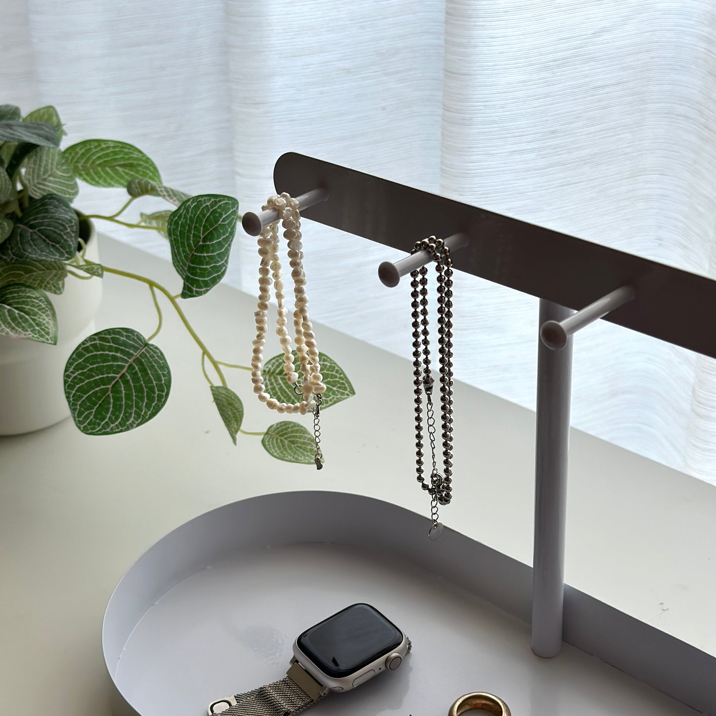 ホワイトのシンプルなアクセサリースタンドにネックレスがかかっている様子