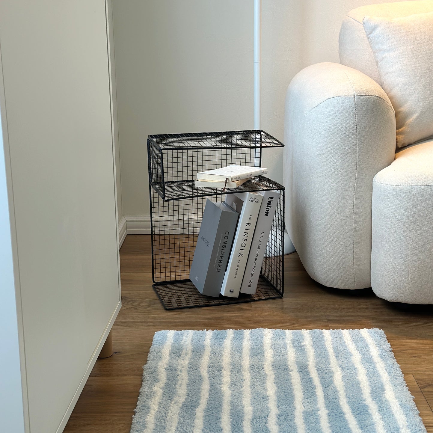 ブラックのメッシュデザインの収納ラックをソファ横に置いている様子