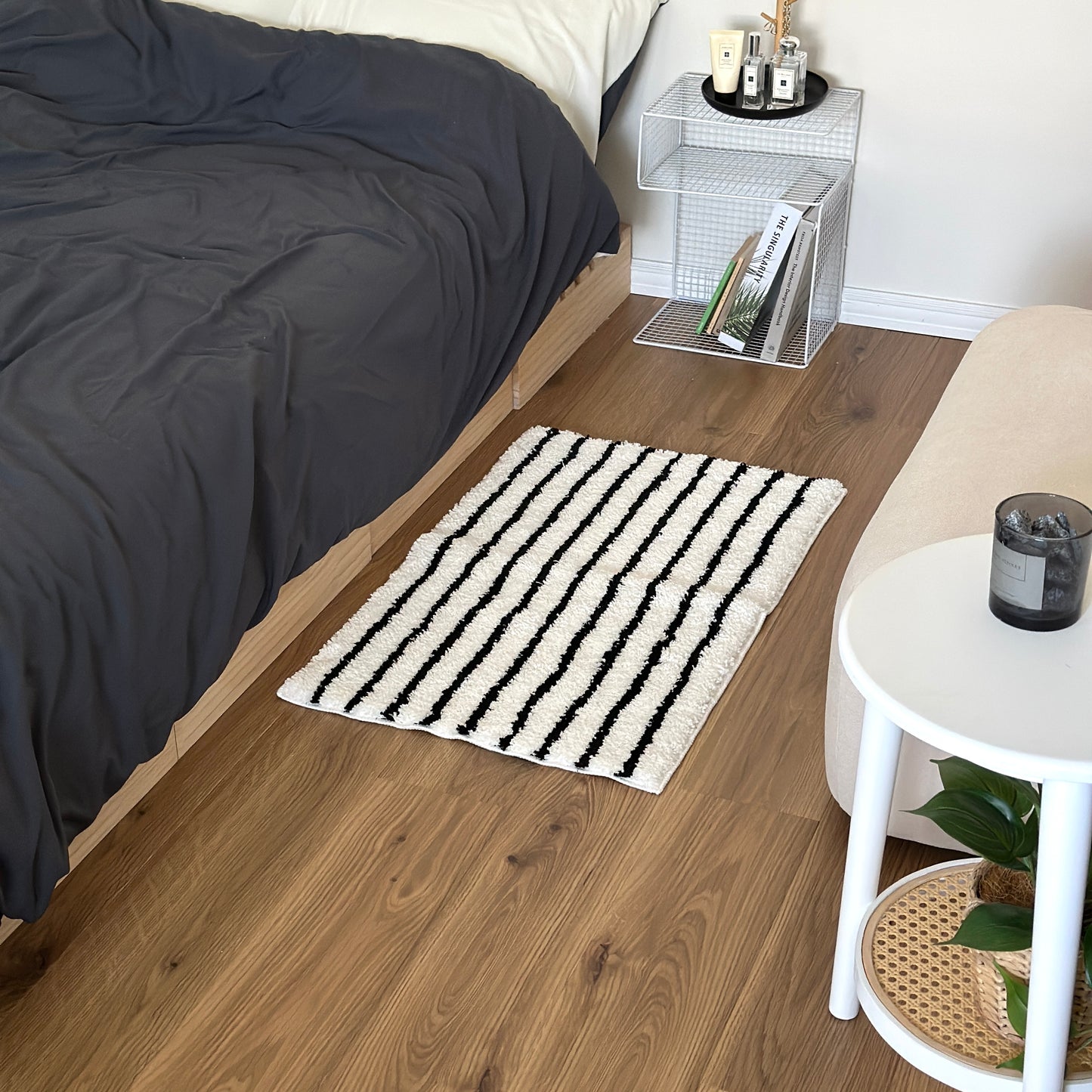 ブラックのシンプルなボーダーミニラグをベッド横に敷いている様子