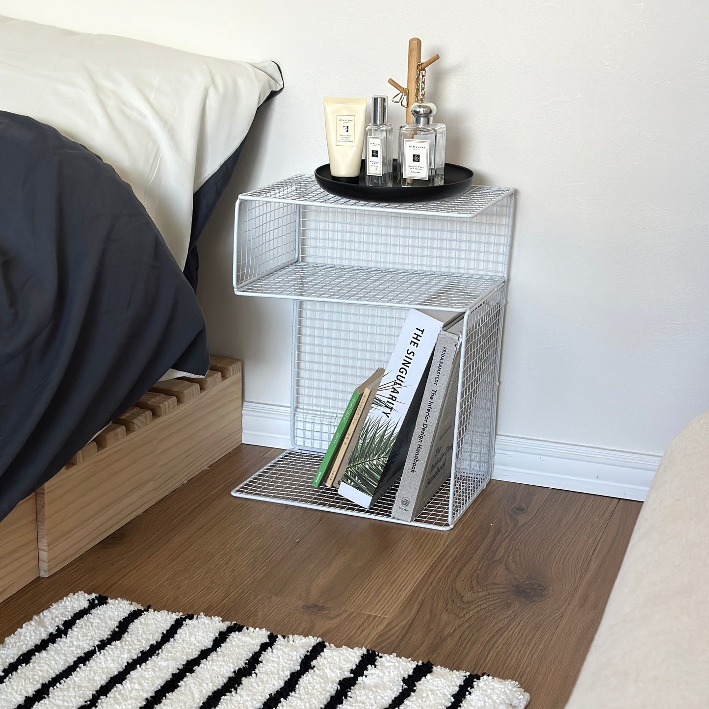 ホワイトのメッシュデザインの収納ラックをベッドサイドに置いている様子