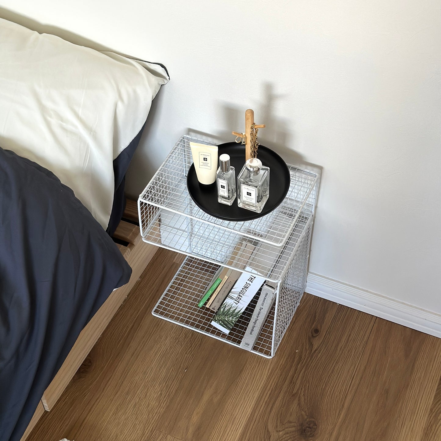 ホワイトのメッシュデザインの収納ラックをベッドサイドに置いている様子