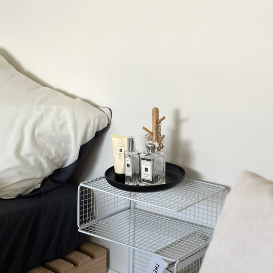 ブラックのプラスチックの丸型トレイと天然木の枝のようなフックのアクセサリースタンドに香水が置かれてある様子