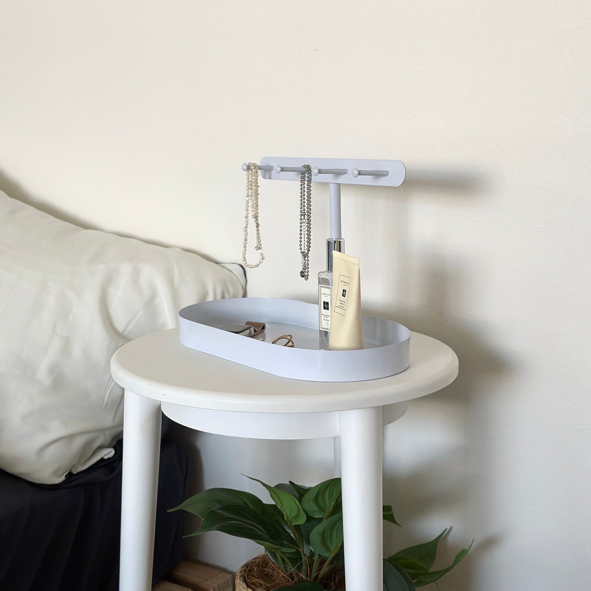 ホワイトのシンプルなアクセサリースタンドがサイドテーブルに置かれてある様子