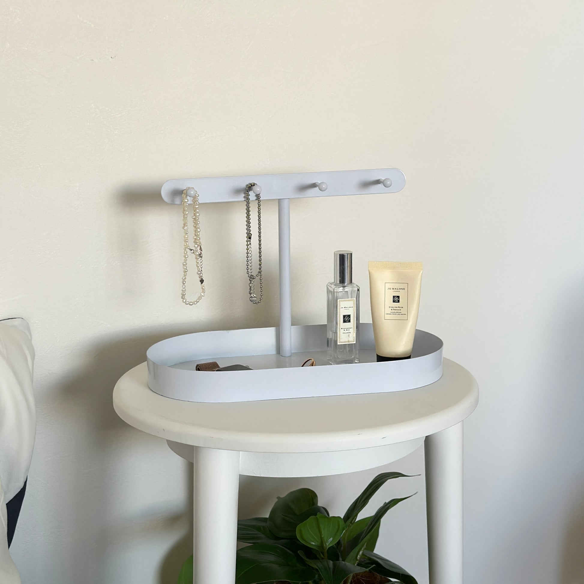 ホワイトのシンプルなアクセサリースタンドをサイドテーブルに置いている様子