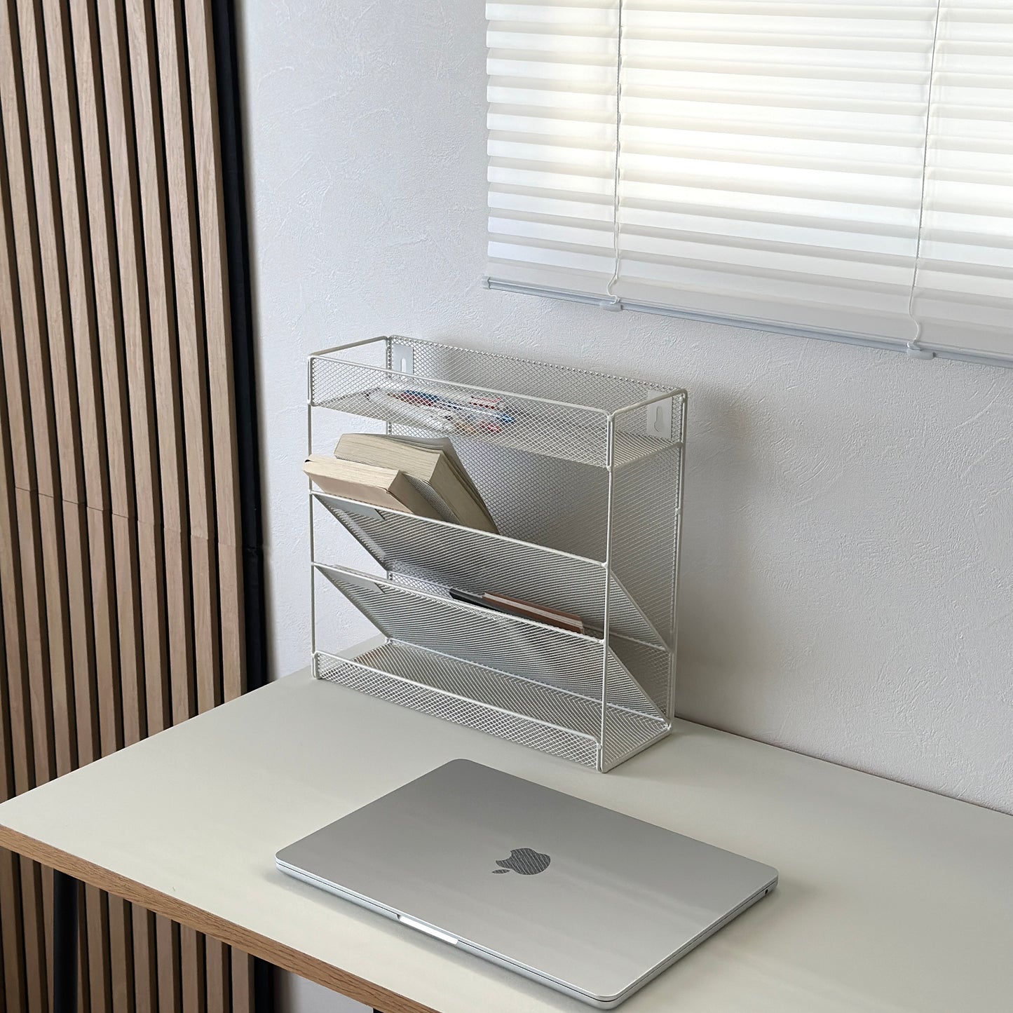 ホワイトのメッシュデザインの4段構造ラックにペンや文庫本を置いている様子