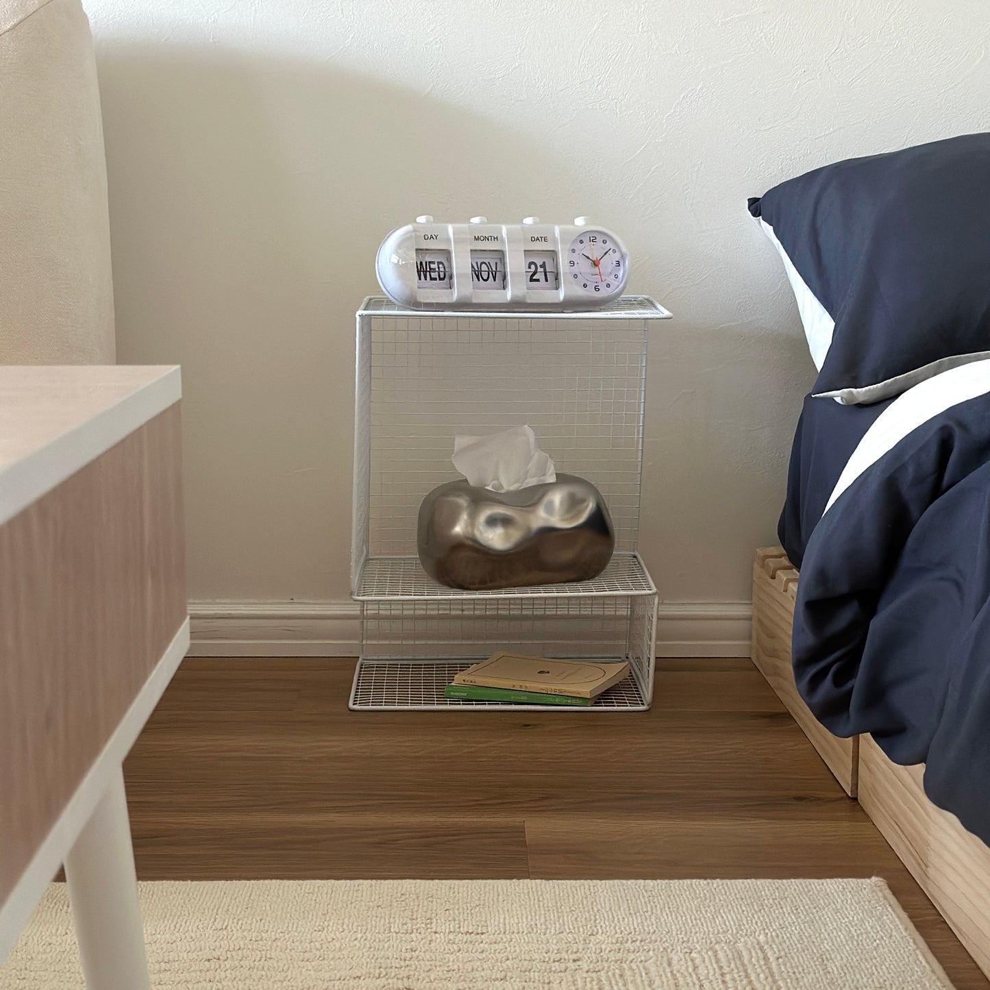 ホワイトのメッシュデザインの収納ラックにティッシュケースや置き時計、文庫本が置かれてある様子