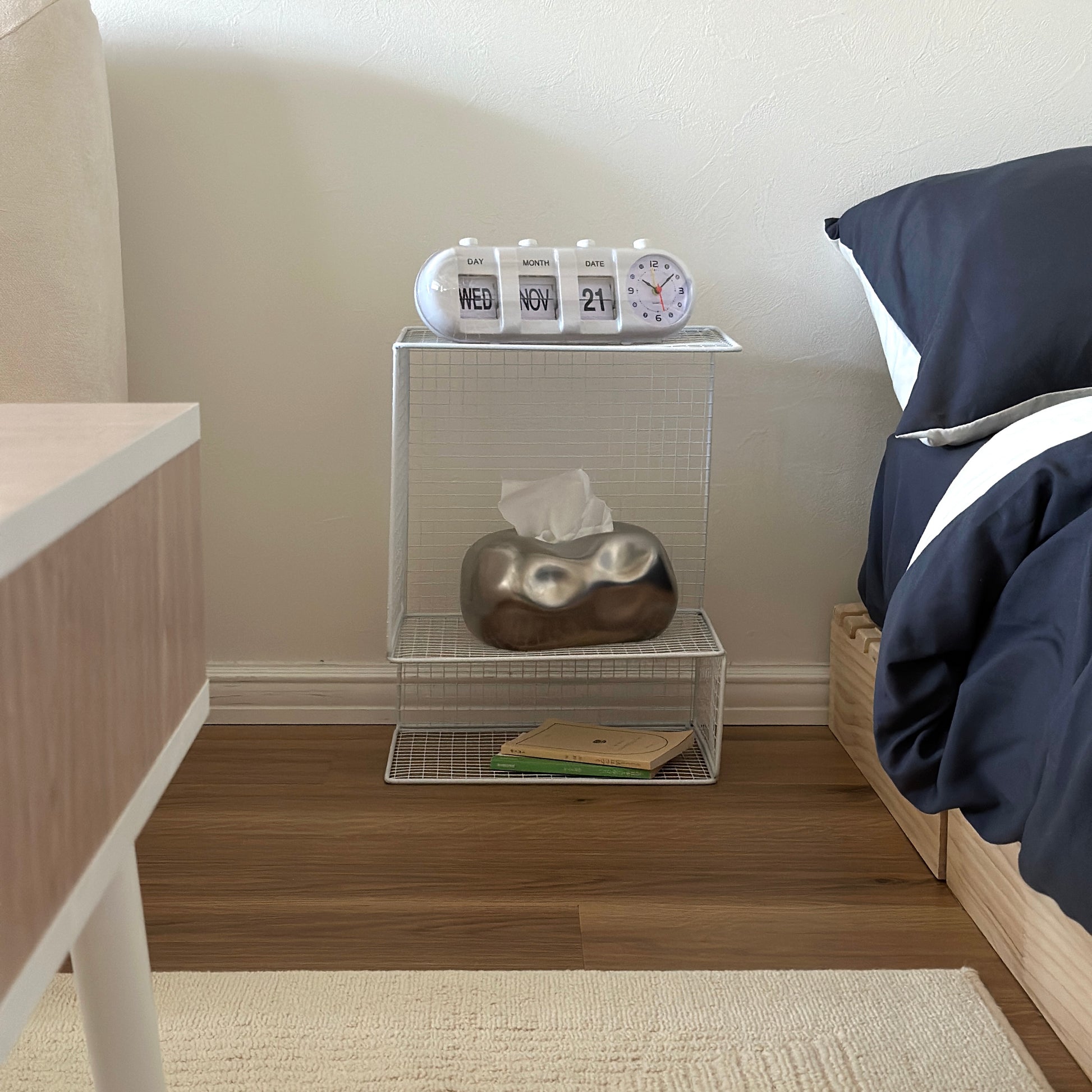 ホワイトのメッシュデザインの収納ラックにティッシュケースや置き時計、文庫本が置かれてある様子