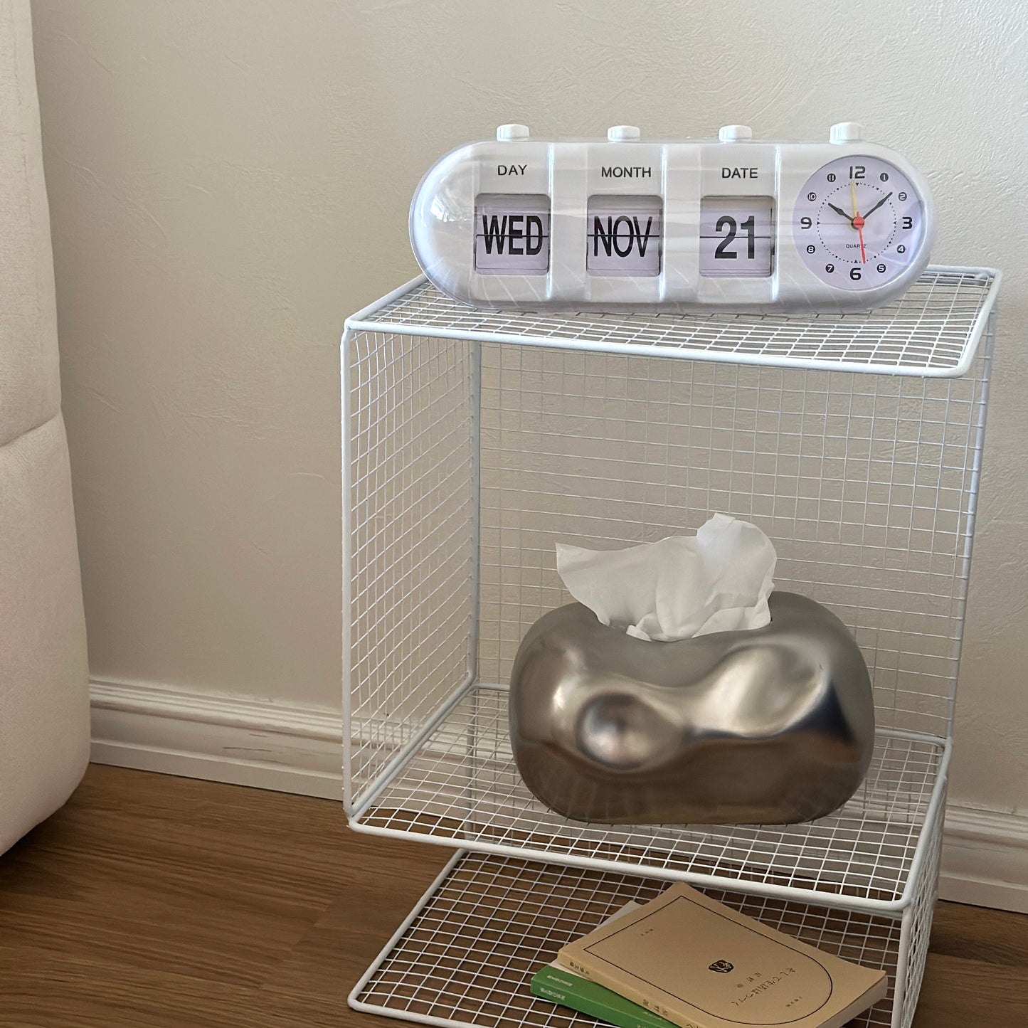 ホワイトのメッシュデザインの収納ラックに置き時計やティッシュケース、文庫本が置かれてある様子