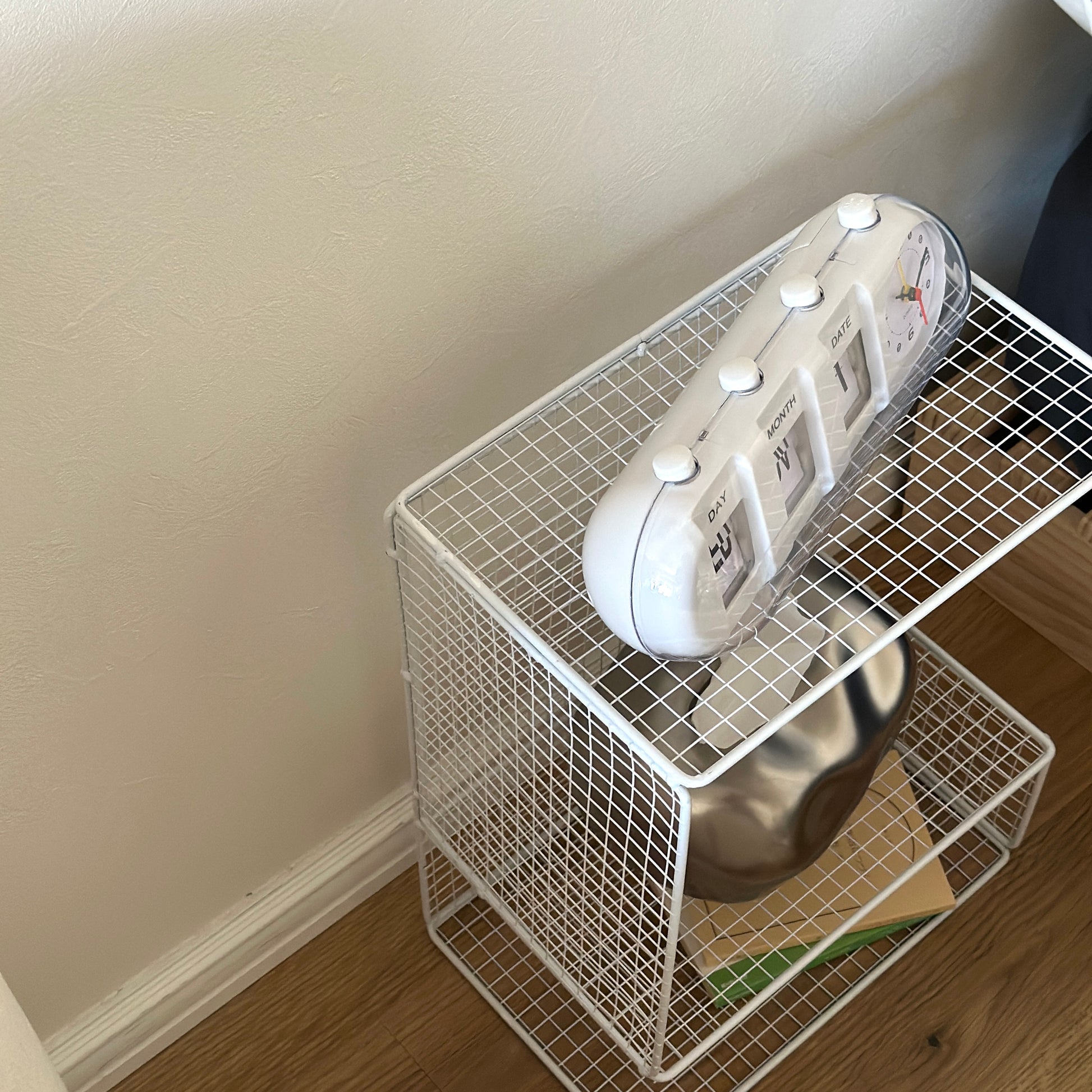 ホワイトのメッシュデザインの収納ラックに置き時計やティッシュケース、文庫本が置かれてある様子