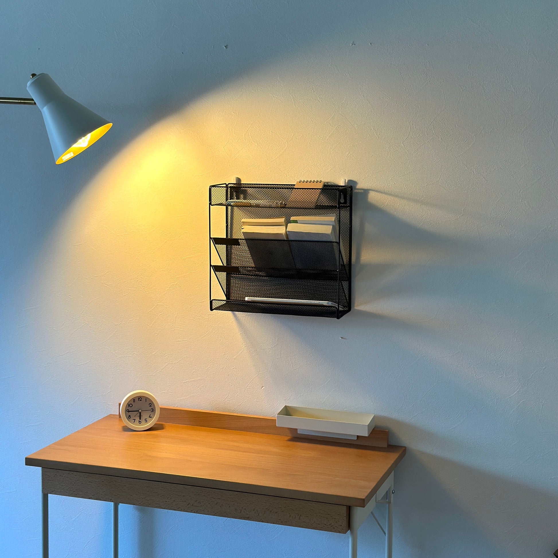 ブラックのメッシュデザインの4段構造ラックを壁にかけている様子