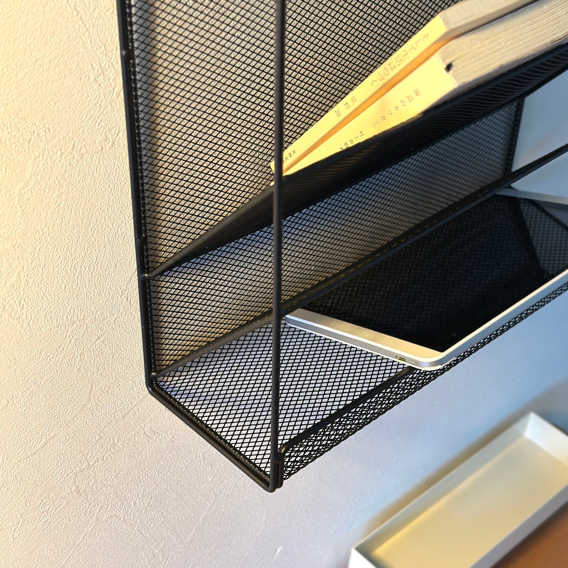 ブラックのメッシュデザインの4段構造ラックにiPadや文庫本が入っている様子