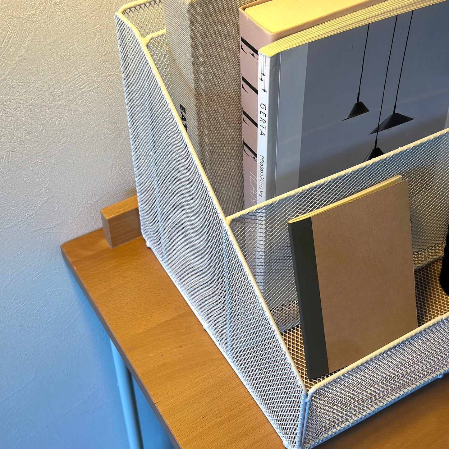 ホワイトのアイアン素材のメッシュ収納ラックに雑誌やメモ帳を入れている様子