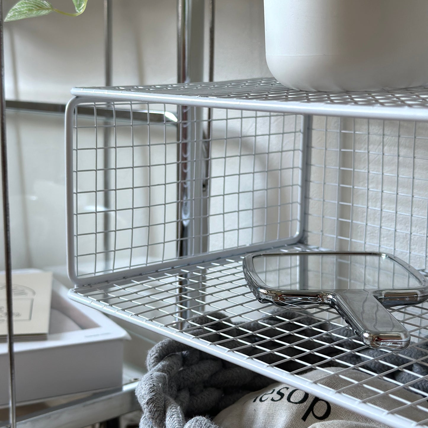 ホワイトのメッシュデザインの収納ラックに手鏡が置かれてある様子