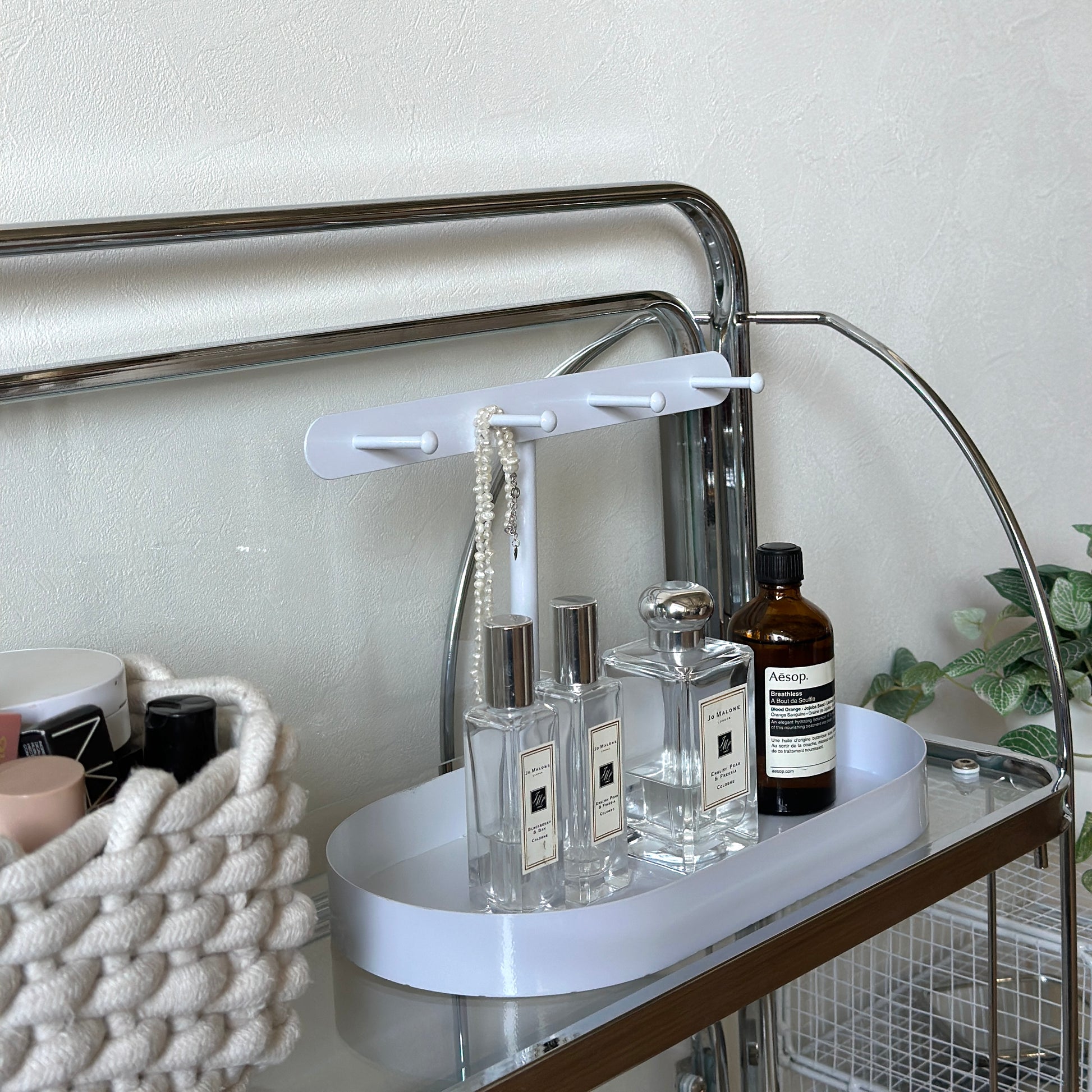 ホワイトのシンプルなアクセサリースタンドに香水をいくつか置いている様子